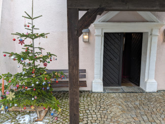 Die Kindergartenkinder schmücken das Weihnachtsbäumchen am Eingang von St. Helena